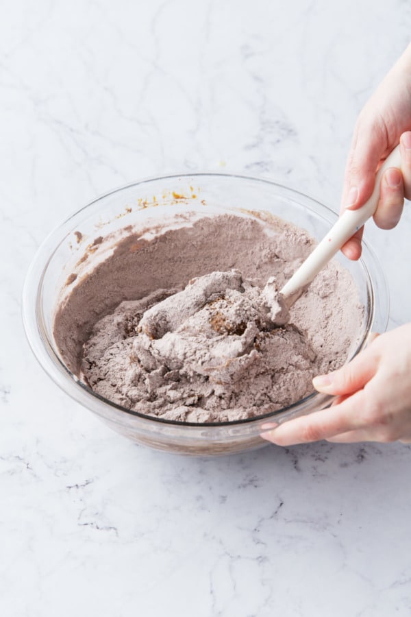 Mixing dry flour into cookie dough with a silicone spatula.