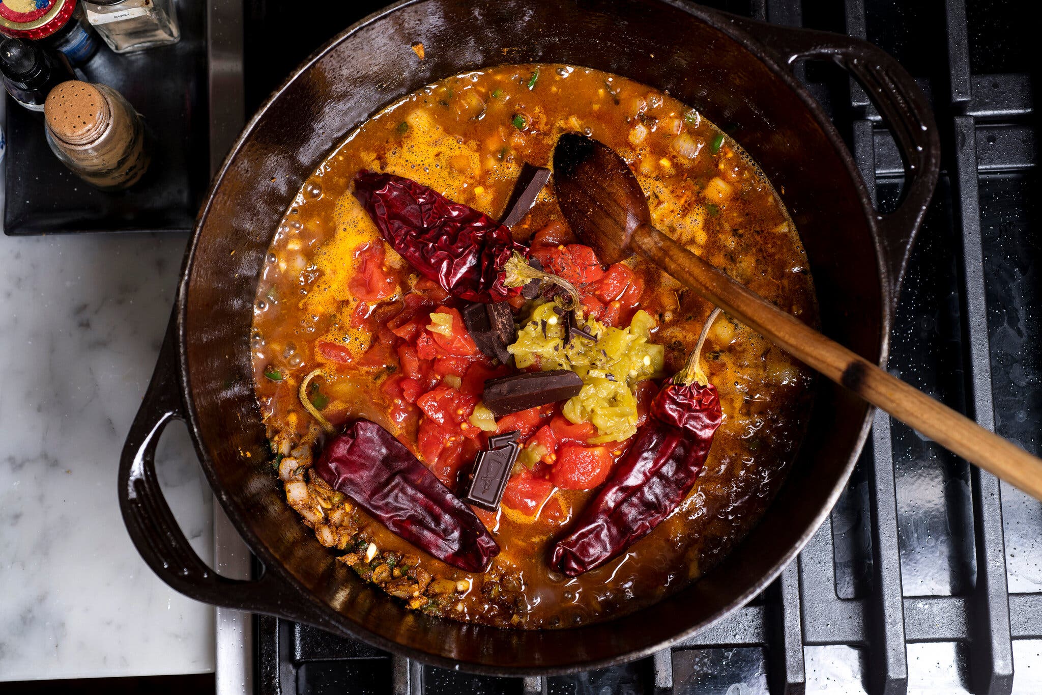 A few peppers are added to the skillet to simmer.