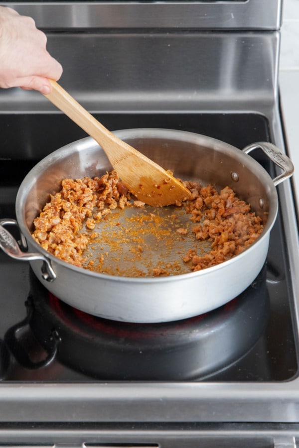 Pushing mostly-cooked Italian sausage out to the edges of the saucepan.