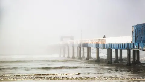 Getty Images Image shows a pier disappearing into sea fog