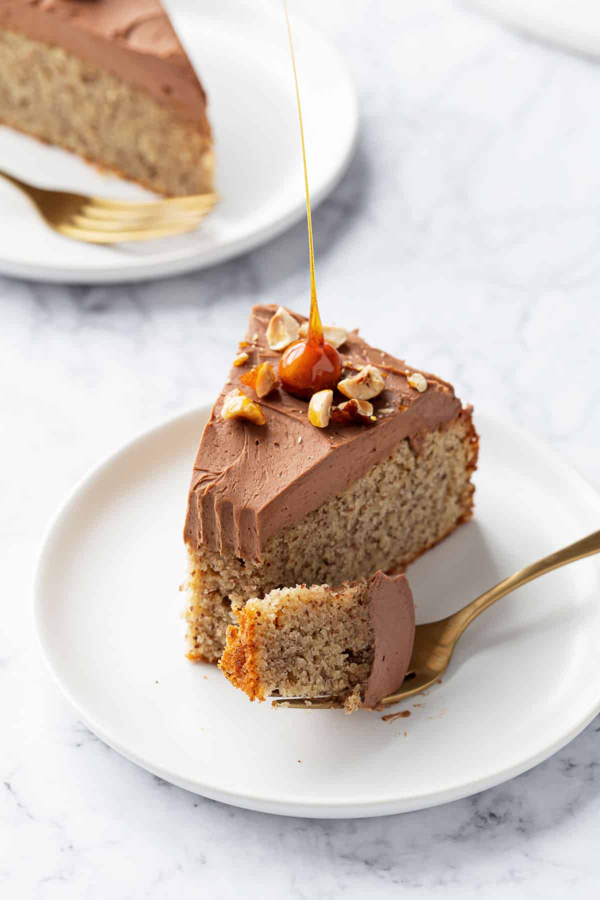 Slice of Flourless Hazelnut Cake with Nutella Whipped Ganache with a bite taken out of it and sitting on a gold fork on the side.