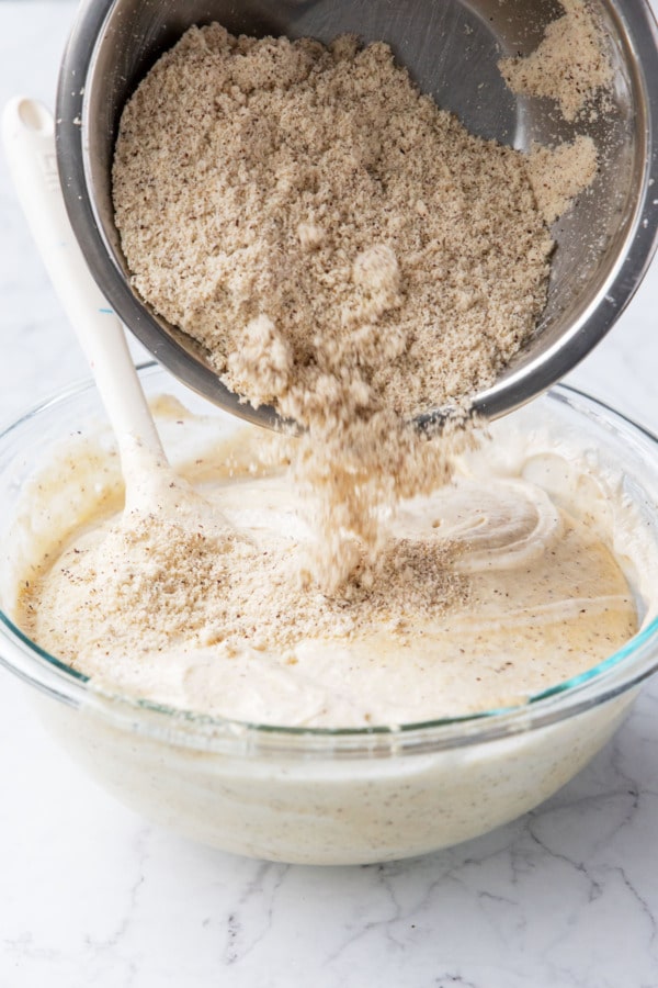 Adding remaining hazelnut flour to the mixing bowl.