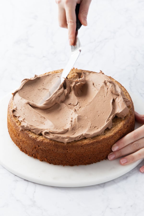 Spreading whipped nutella ganache onto finished cake with an offset spatula.