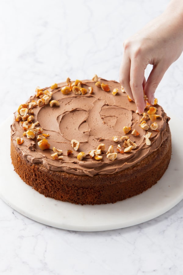 Sprinkling top of cake with chopped candied hazelnuts around the edge.