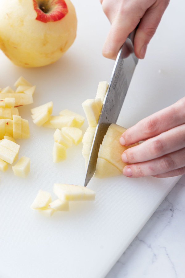 Dicing peeled apple into roughly 1/2-inch pieces.