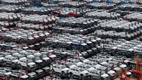 Getty Images This aerial photograph taken on April 16, 2024 shows electric cars for export stacked at the international container terminal of Taicang Port in Suzhou, in China's eastern Jiangsu Province. 