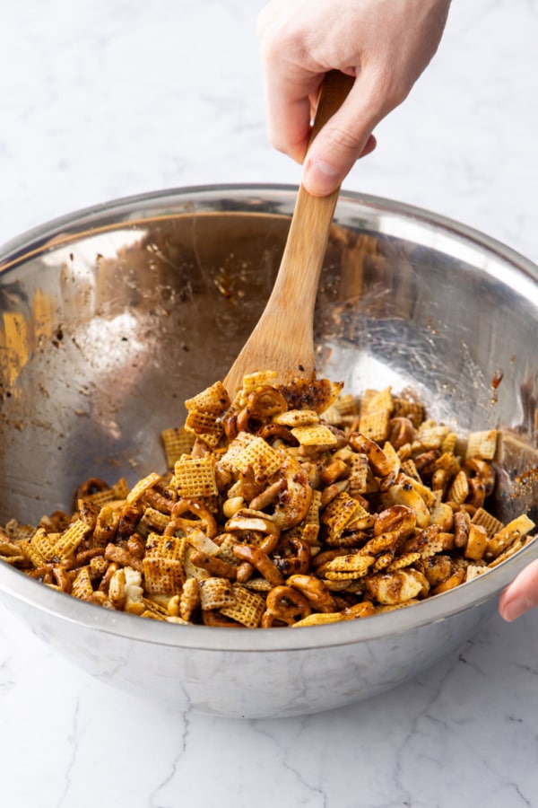 Stirring snack mixture to evenly coat with sauce.