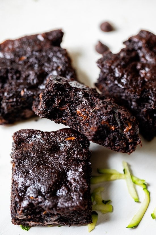 These easy Flourless Zucchini Brownies are made with almond meal, so they're naturally gluten-free. They're moist, fudgy, and so decadent! Flourless Zucchini Brownies piled on parchment paper