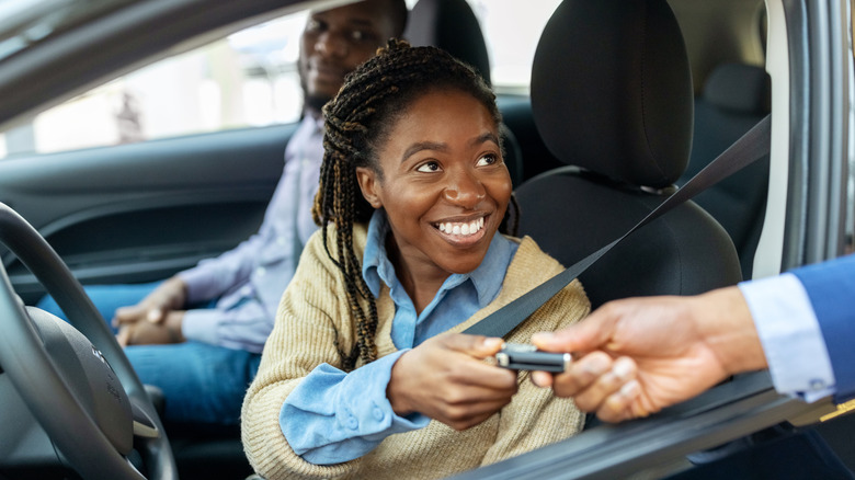 Couple receiving the keys to a new car.