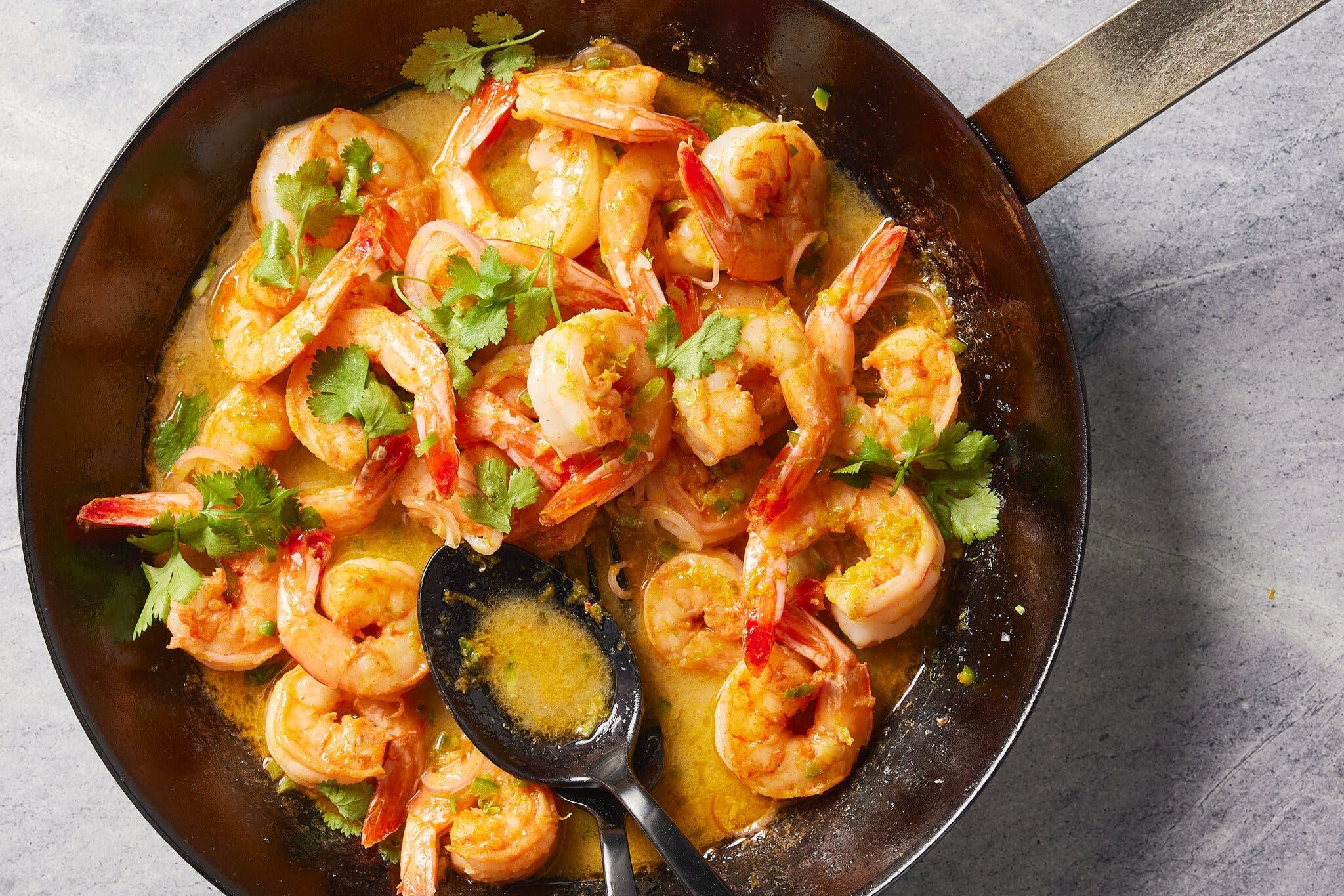 An overhead image of shrimp in a skillet filled with a citrusy sauce.