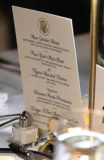 Elegant dinner table setting with a menu, yellow roses, and a number 40 card displayed, suggesting a formal or special occasion