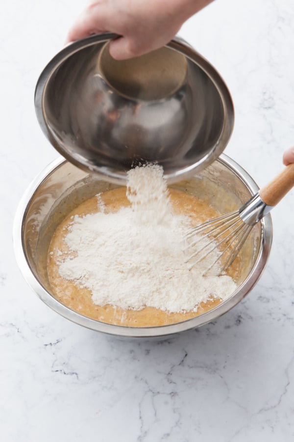 Adding remaining half of dry flour mixture to mixing bowl with other ingredients.
