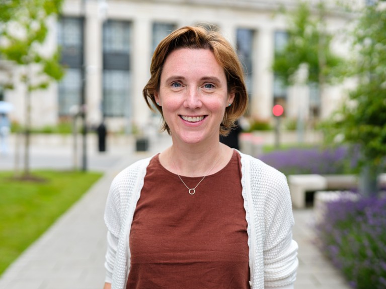 Portrait of Lorna Dougan outside a large building with trees and plants.