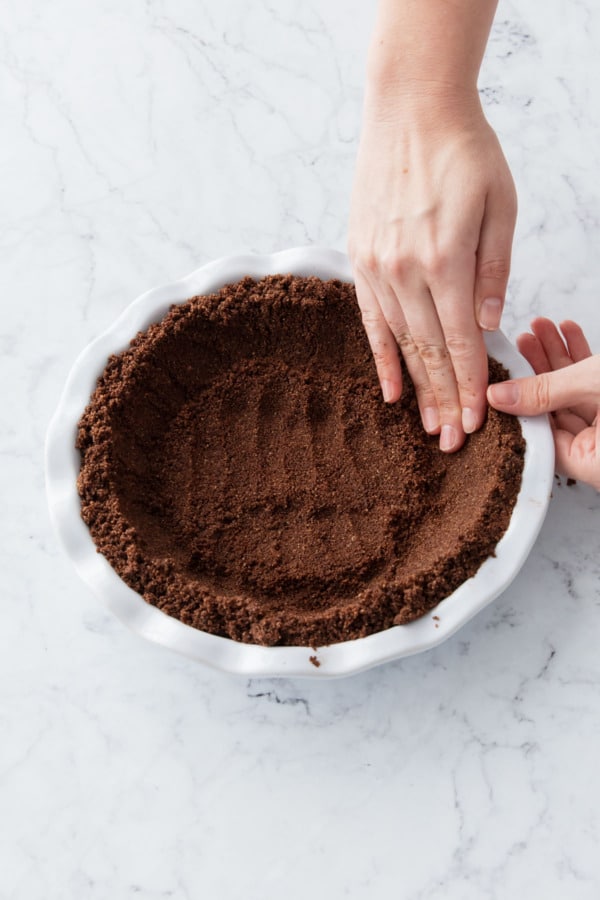 Pressing chocolate graham cracker crumbs into pie plate.