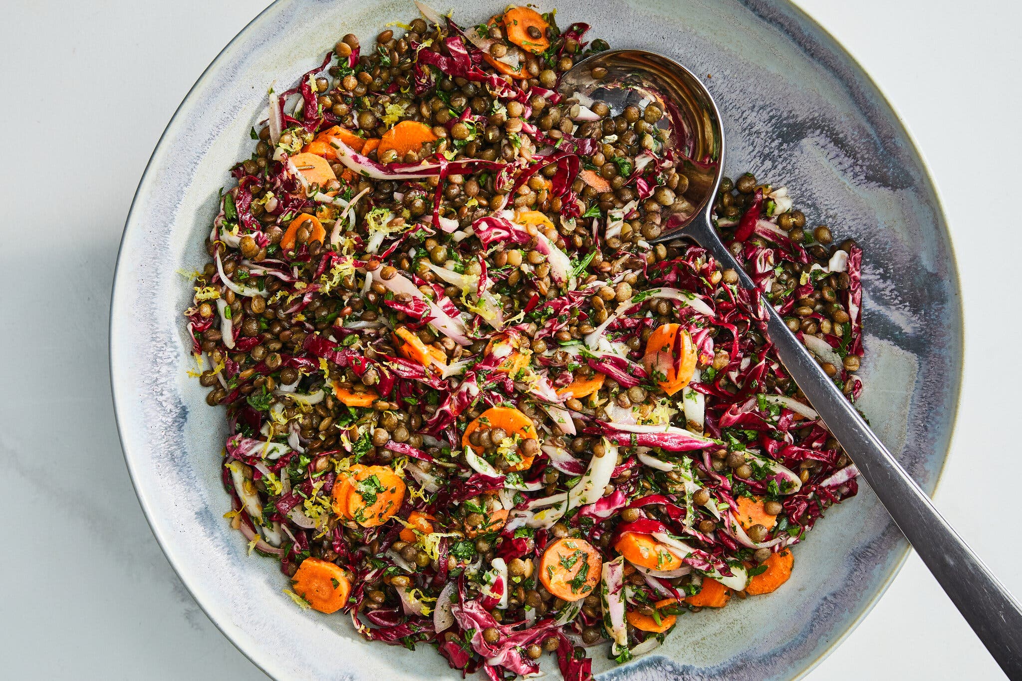 An overhead image of a lentil salad studded with carrots and herbs.