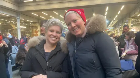 Haley Adams and Hannah Hagar stand in coats in London St Pancras International