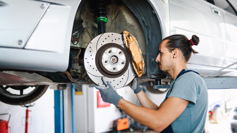 Mechanic inspects the rear brakes of a performance sedan