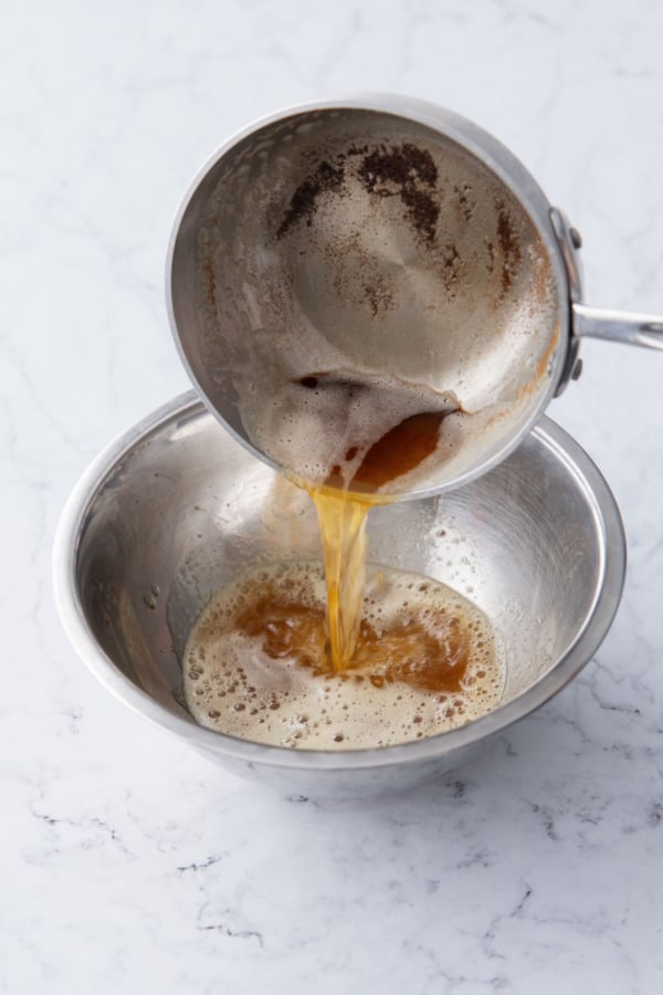 Pouring browned butter into a metal mixing bowl.
